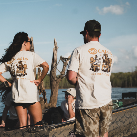 A couple wearing the No Calls Tee on a boat at the sandbar, enjoying the off-season with a relaxed and playful design.