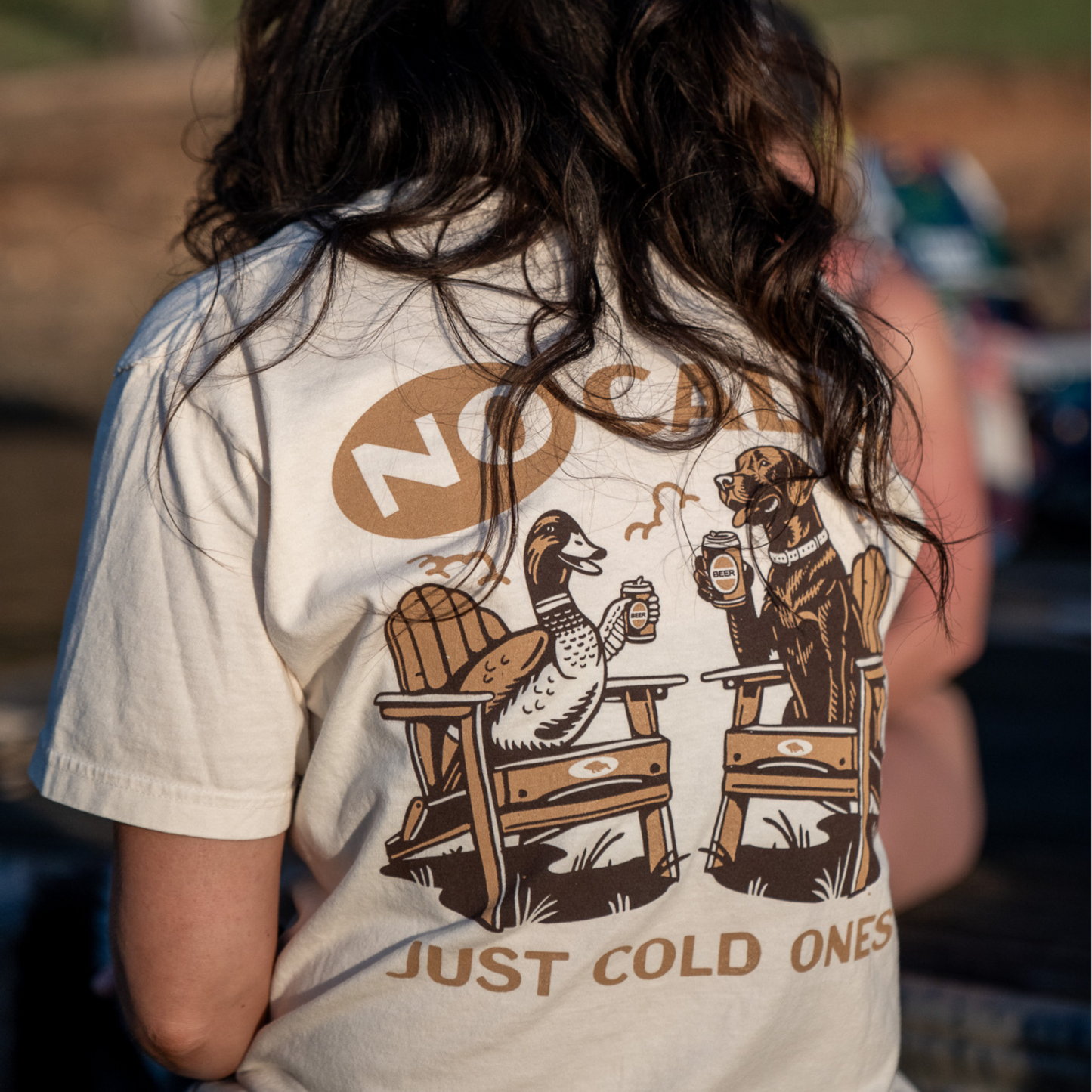 Close-up of a woman wearing the No Calls Tee, made from ultra-soft Comfort Colors fabric, with the duck and dog design on the back visible.