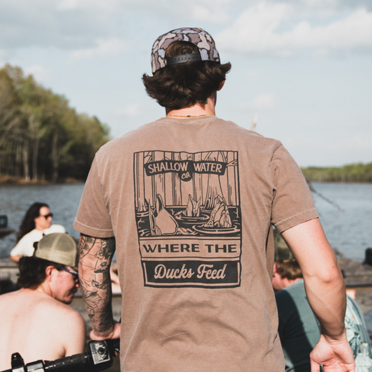 Close-up of a man wearing the Where the Ducks Feed Tee, enjoying time on the water, with a relaxed fit perfect for outdoor adventures.