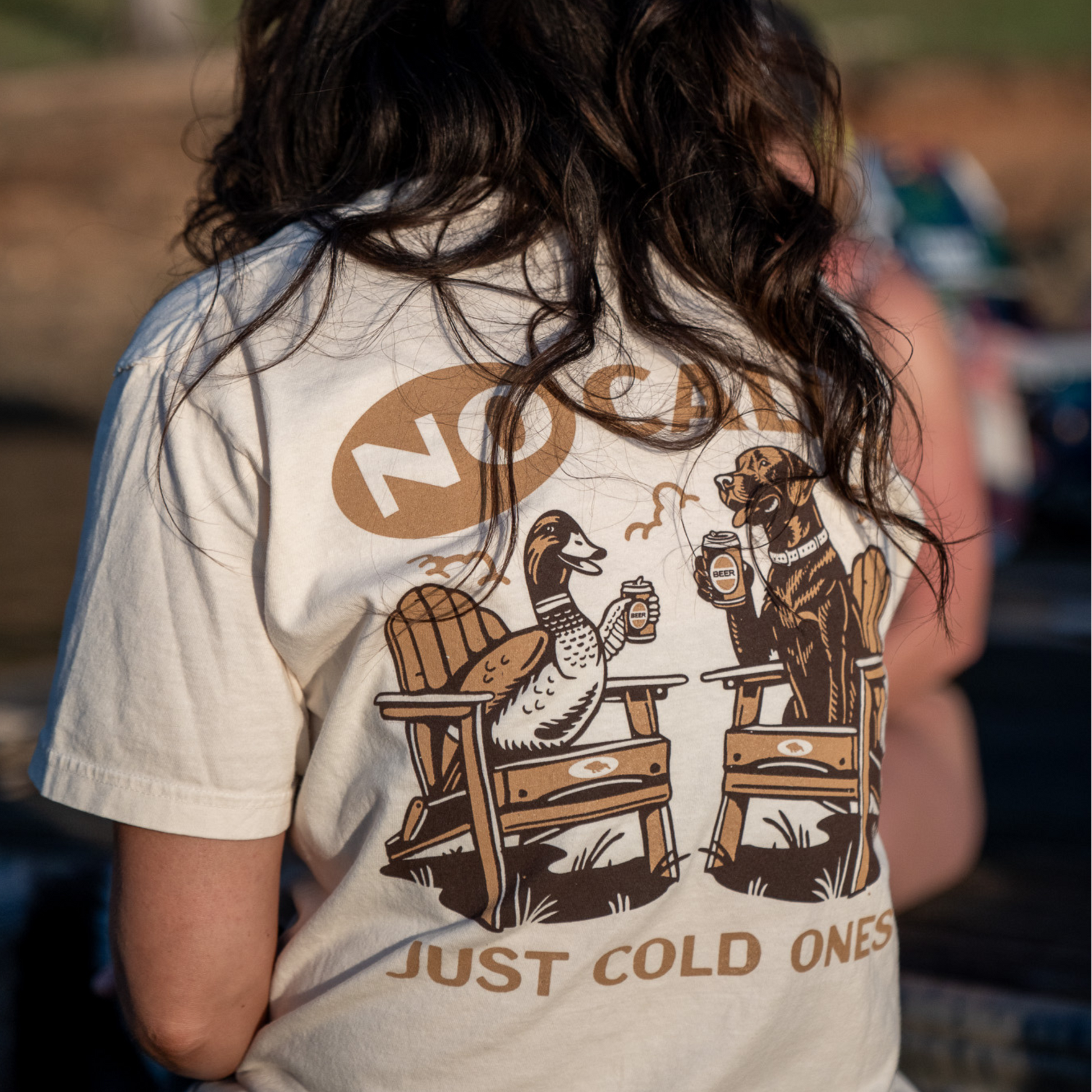 Close-up of a woman wearing the No Calls Tee, made from ultra-soft Comfort Colors fabric, with the duck and dog design on the back visible.
