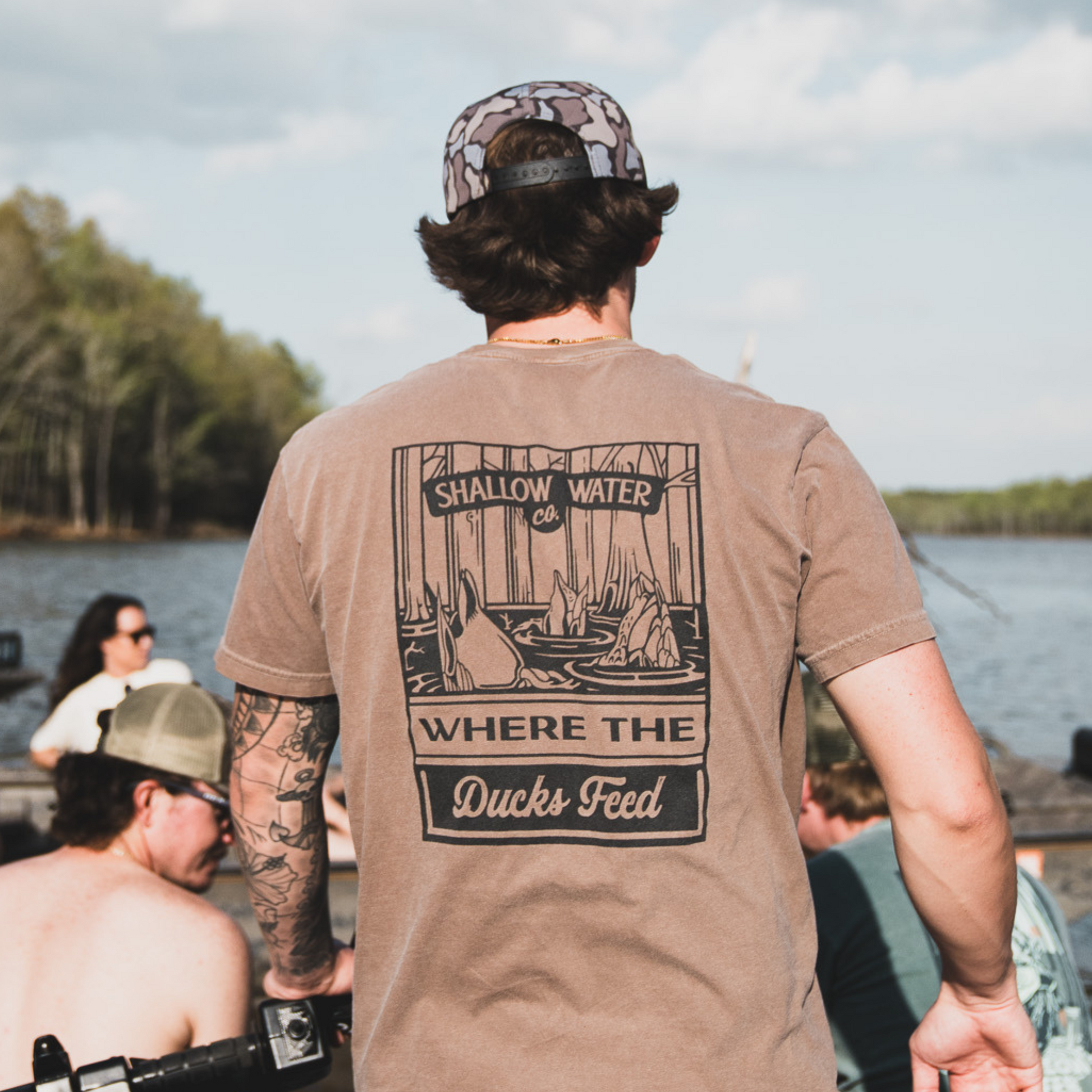 Close-up of a man wearing the Where the Ducks Feed Tee, enjoying time on the water, with a relaxed fit perfect for outdoor adventures.