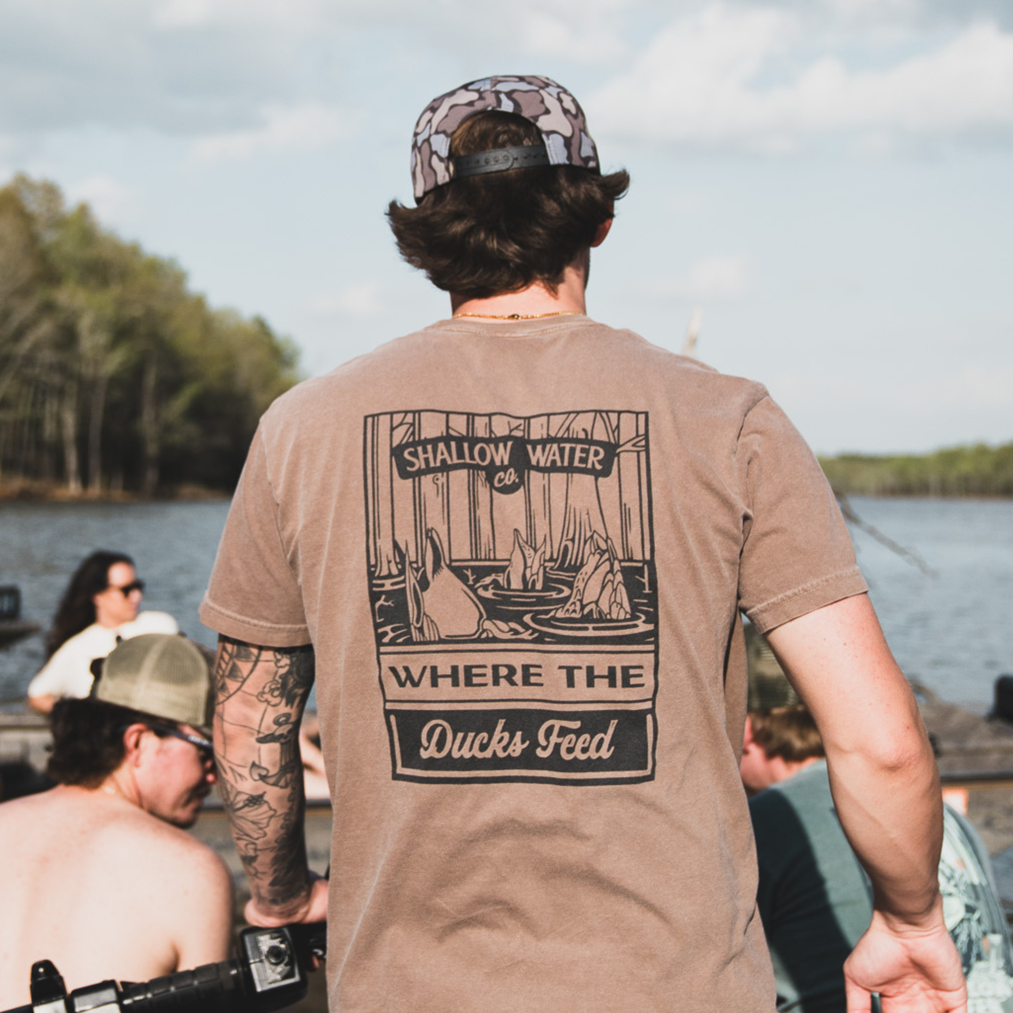 Close-up of a man wearing the Where the Ducks Feed Tee, enjoying time on the water, with a relaxed fit perfect for outdoor adventures.